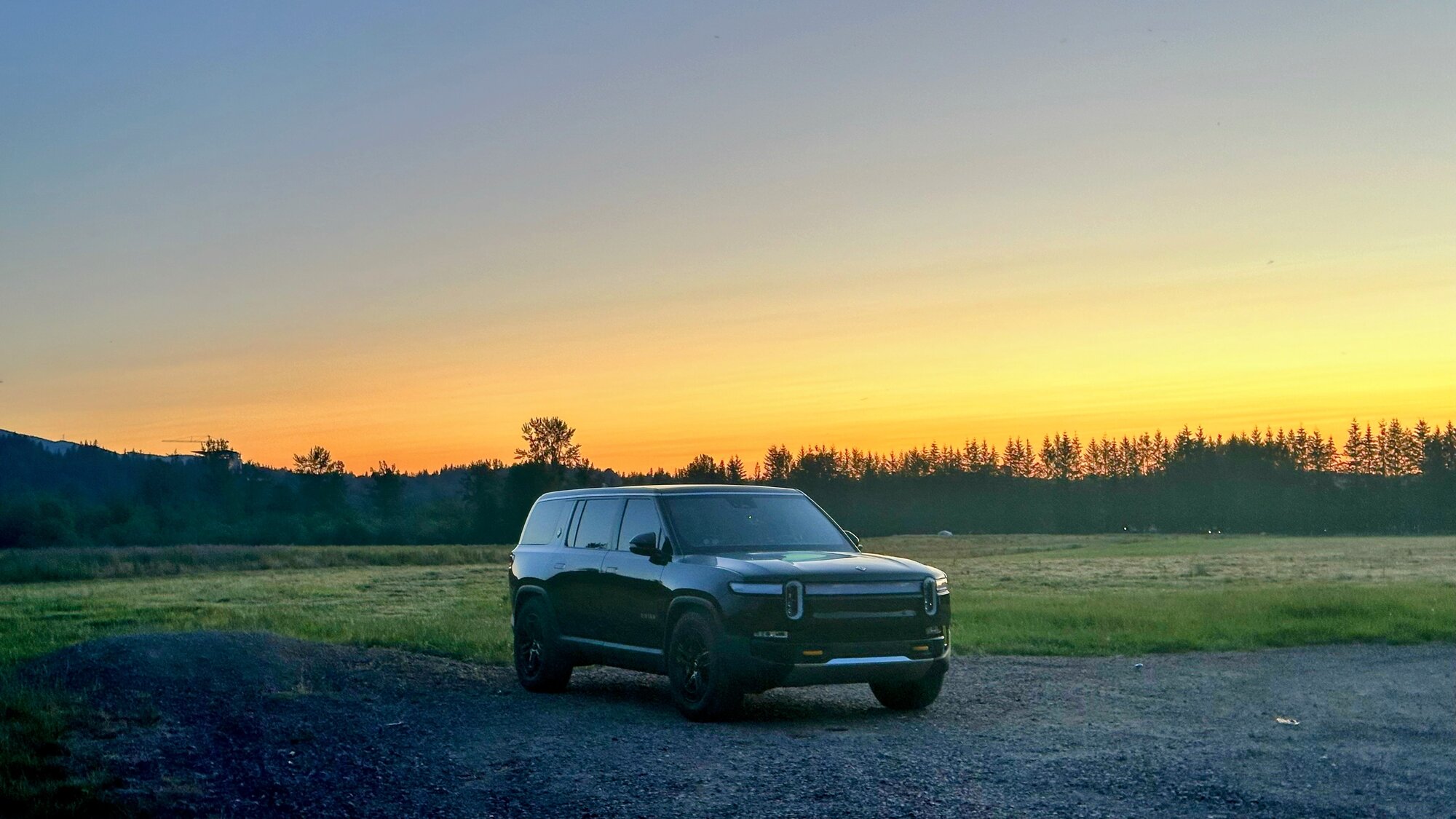 Rivian R1S silhouetted against a mountain sunset