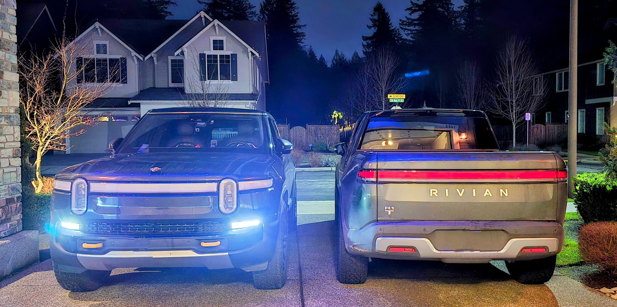 The R1S and R1T parked together at night, lights on