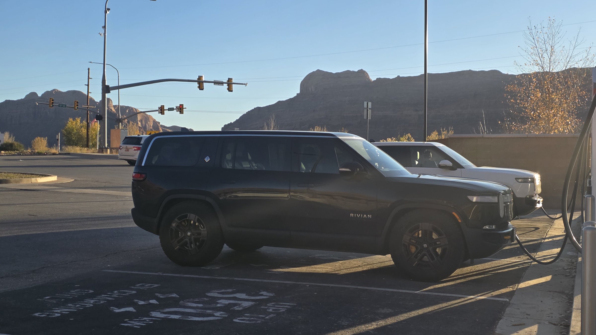 R1S charging at Electrify America in Moab with red rock cliffs behind