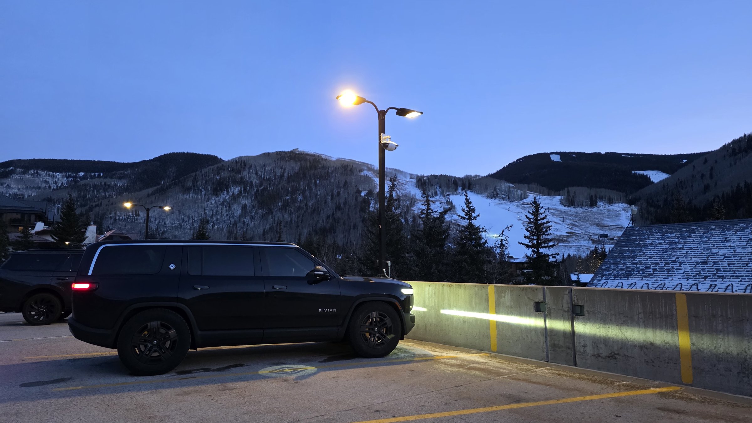 R1S parked in Vail with ski slopes and snowy mountains behind
