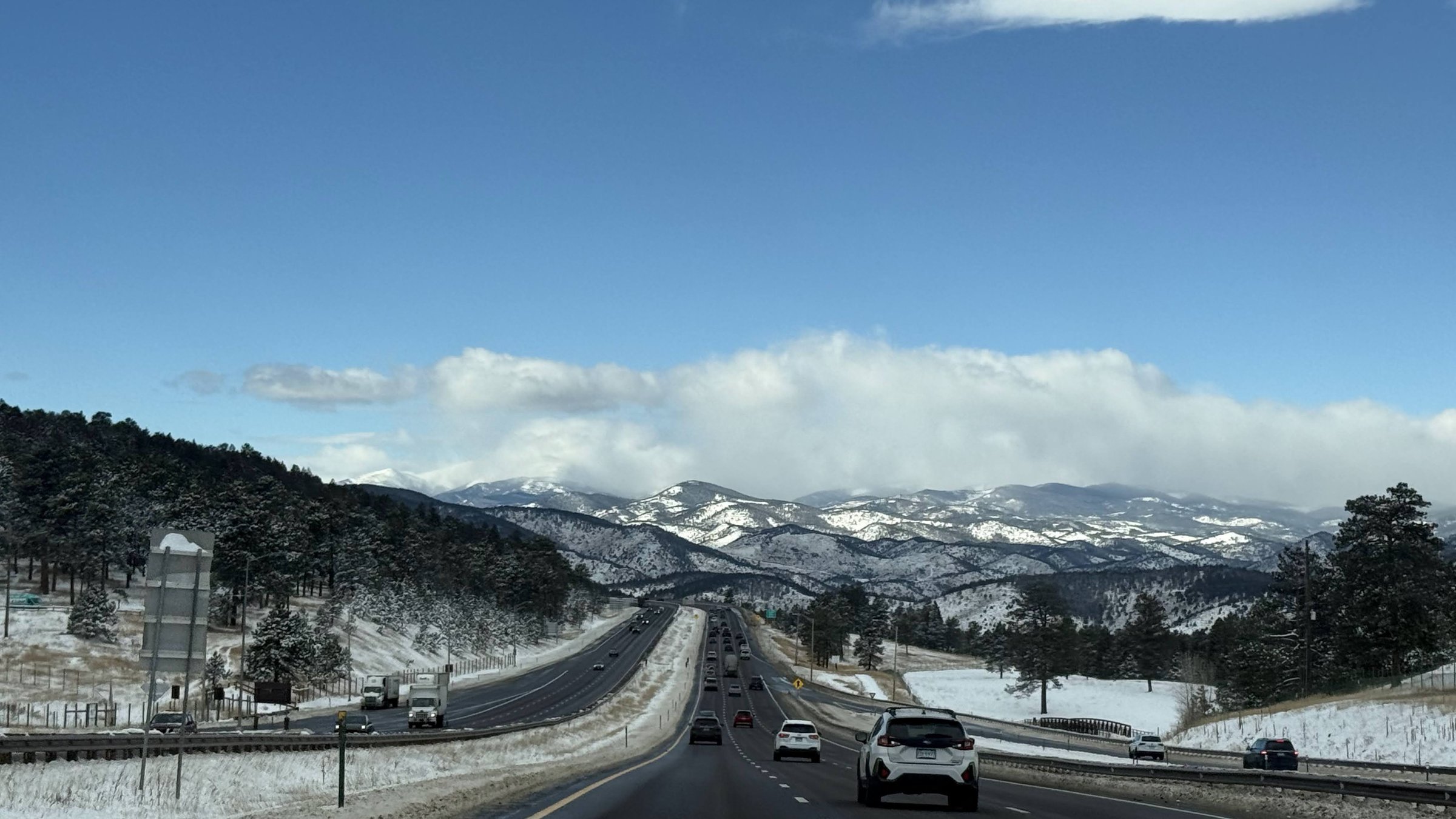 I-70 through the snowy Rocky Mountains with wide highway and mountain views